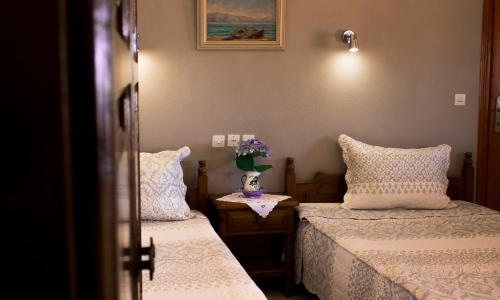 a bedroom with two beds and a vase of flowers on a table at Lefteris Studios in Lefokastro