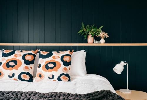 a bedroom with a green wall and a bed with pillows at Laneway Apartments - Orientem in Port Fairy