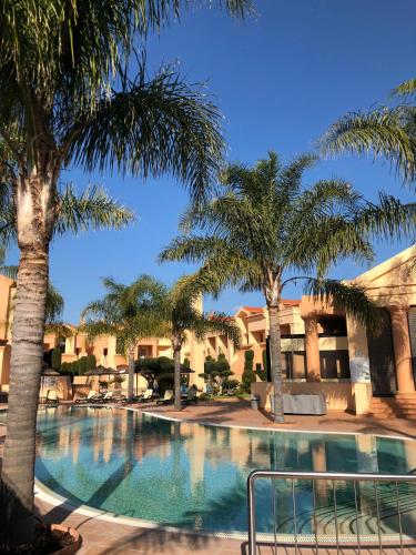 a swimming pool with palm trees in a resort at Rother Praia da Luz Luxury Apartment in Luz