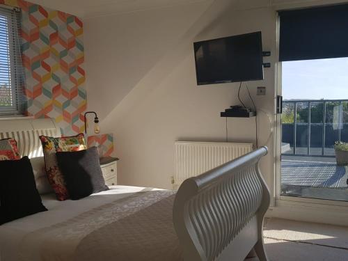 a bedroom with a bed with a television on the wall at Telscombe Cliffs Bed and Breakfast in Rottingdean