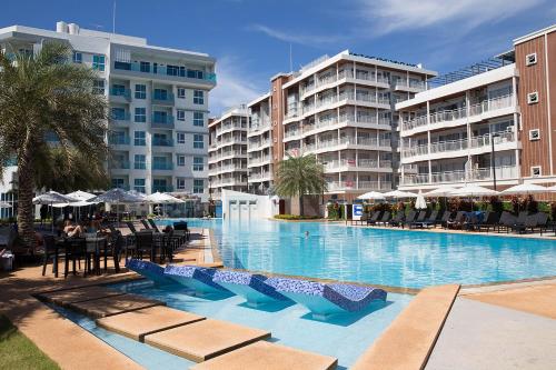 a large swimming pool with tables and chairs and buildings at Grandblue Condominium 708 in Ban Nam Lai Ta Tum