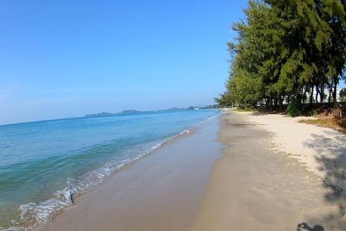 a beach with trees and the ocean on a sunny day at Grandblue Condominium 708 in Ban Nam Lai Ta Tum