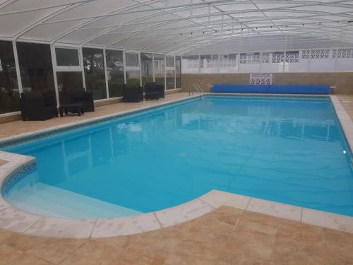 a large swimming pool with blue water in a building at Valley Grove Bungalows in Saundersfoot
