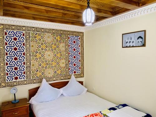 a bedroom with a bed and a painting on the wall at Sukhrob Barzu Hotel in Bukhara