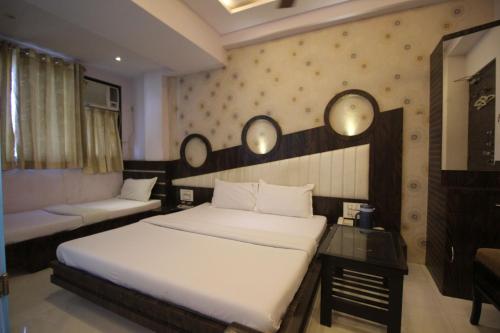 a bedroom with two beds and a table and mirrors at Hotel Navi Mumbai in Navi Mumbai