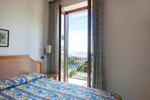 una camera con letto e porta scorrevole in vetro di La Capannina - Hotel & Apartments a Ischia