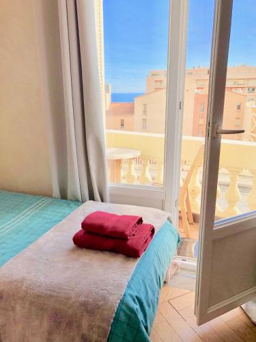 un lit dans une chambre avec une grande fenêtre dans l'établissement appartement Monaco Beausoleil, à Beausoleil