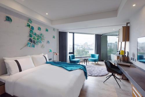 Schlafzimmer mit einem großen weißen Bett und einem Schreibtisch in der Unterkunft Brio Hotel in Kaohsiung