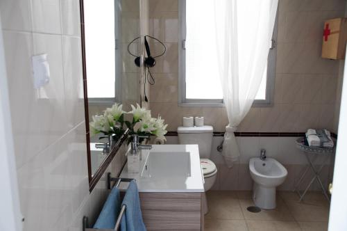 マラガにあるHoliday Suitesの白いバスルーム(洗面台、トイレ付)