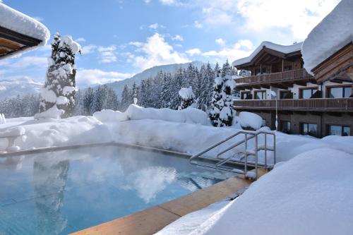 a swimming pool covered in snow next to a lodge at Leamwirt in Hopfgarten im Brixental