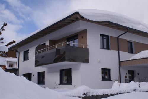 a building covered in snow with a balcony at Appartement Waldblick in Leogang