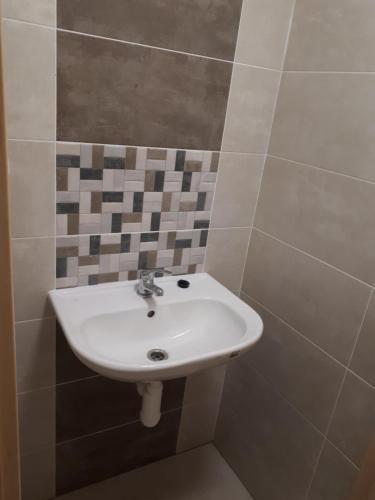 a white sink in a bathroom with tiles on the wall at Buchtův statek in VendolÃ­
