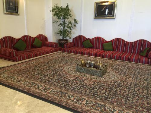 a living room with two red couches and a rug at Hotel Al Madinah Holiday in Muscat