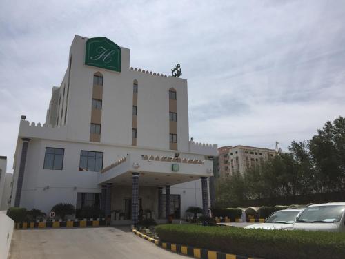 a hotel in a parking lot with cars parked in front at Hotel Al Madinah Holiday in Muscat