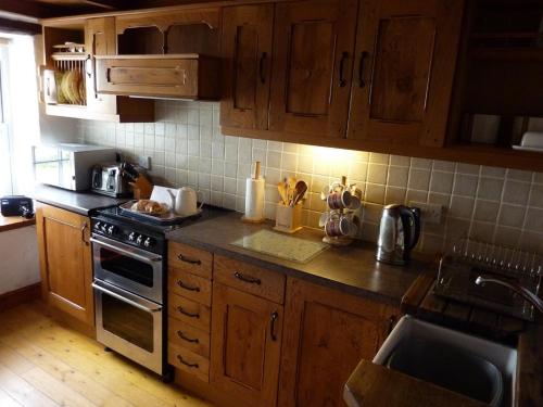 een keuken met houten kasten en een fornuis met oven bij Engellie Cottage in Perranporth