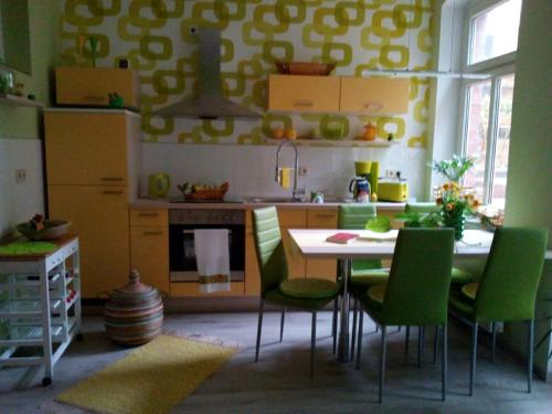 una cocina con mesa y algunas sillas verdes en Ferienwohnung Halle Saale en Halle an der Saale
