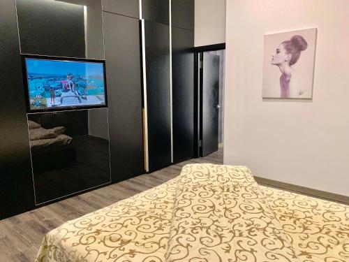 Schlafzimmer mit einem Bett und einem Flachbild-TV in der Unterkunft Сучасні апартаменти на площі Ринок з панорамним видом на дахи Львова in Lwiw