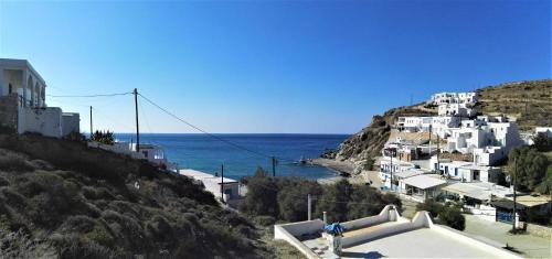 un grupo de edificios blancos en una colina junto al océano en Perigiali Rooms & Apartments Folegandros en Agali