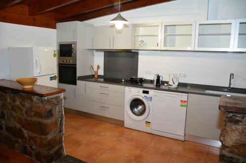 a kitchen with white cabinets and a washing machine at Solar Arco de São Jorge in Santana