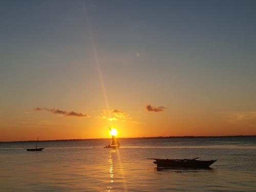 a sunset with two boats in the water at Michamvi Spirit Lodge in Michamvi