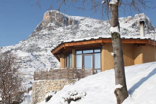 a house in the snow with a mountain behind it at Eco Village Under the Cliffs in Ilindentsi