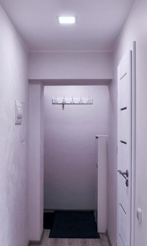 a hallway with a white room with a door at Butas miesto centre in Panevėžys