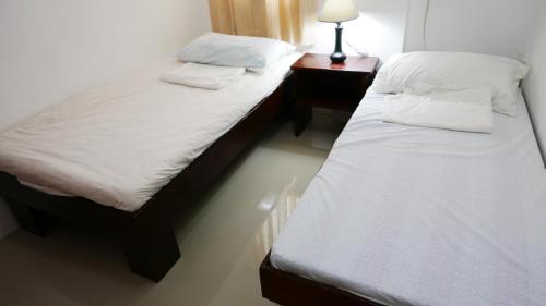 2 aparte bedden in een kamer met een nachtkastje bij JSB Residences Cebu B-flat in Consolation