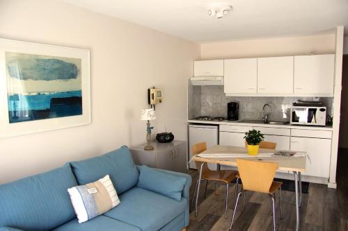 ein Wohnzimmer mit einem blauen Sofa und einem Tisch in der Unterkunft Bilderdijklaan 8 Château Petit Sable in De Haan