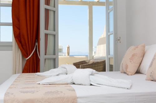 a bedroom with a bed with white sheets and a window at Sun and Moon Villas in Aliko Beach