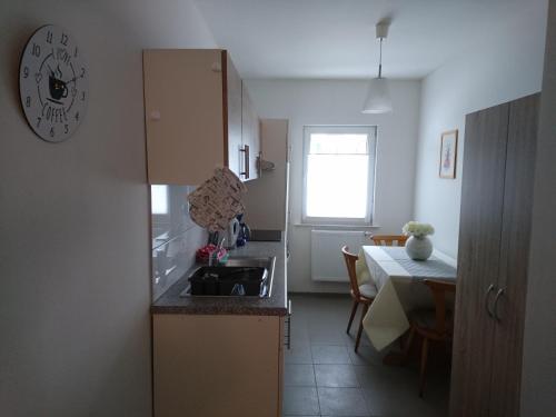 a kitchen with a sink and a table and a clock at Pension Turm in Schönwald