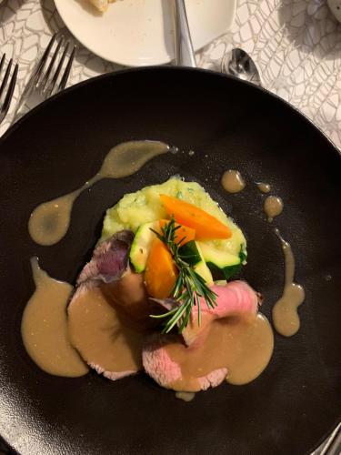 a plate of food with meat and vegetables in a sauce at Feldmilla Design Hotel - Wellness & SPA in Campo Tures