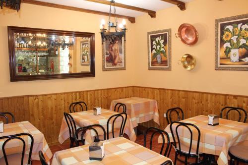 Un restaurante con mesas y sillas y un espejo. en Apartamentos Haza La Moraleda, en Güéjar-Sierra