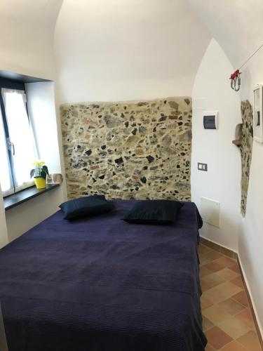 een slaapkamer met een bed met een stenen muur bij Le Ciappe Castelbianco Cielo CITR 9020-BEB-0003 in Castelbianco