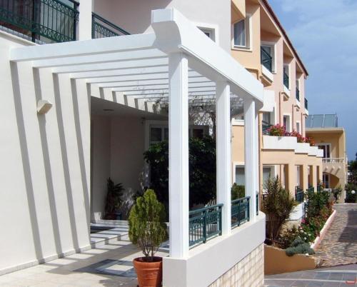 a white pergola on the side of a building at Alexia Beach Hotel in Agia Marina Nea Kydonias