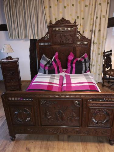 a wooden bed with pink and black pillows on it at Ferienhof Schmickerath in Simmerath