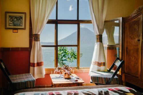 a bedroom with a large window and a table and chairs at Hotel La Casa del Mundo in Jaibalito