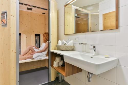 a woman is sitting in a bath tub in a bathroom at Kronhofer – Apartments & Erlebnis-Imkerei in Hermagor