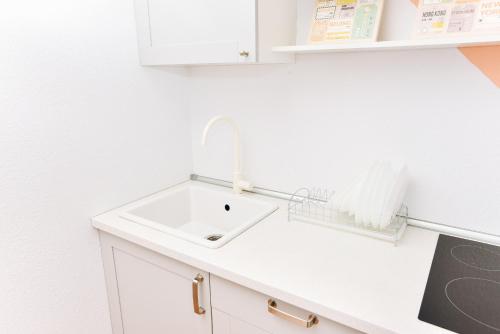 a white kitchen with a sink and a counter at Apartment Tatiana in Yekaterinburg