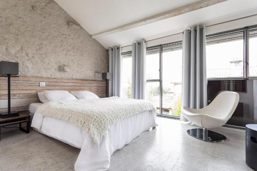 a bedroom with a white bed and a white chair at Le392Bis in Échiré