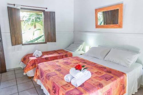 a hotel room with two beds with towels and flowers at Pousada Varanda do Sol in Arraial d'Ajuda