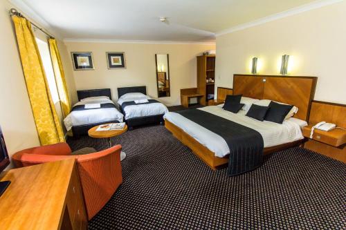 a hotel room with two beds and a television at Padbrook Park Hotel in Cullompton