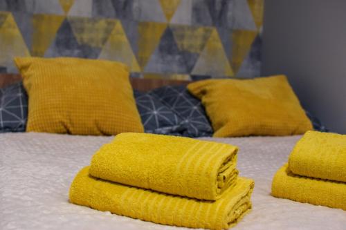 Una cama con toallas amarillas encima. en Mogilska Tower + garaż en Cracovia