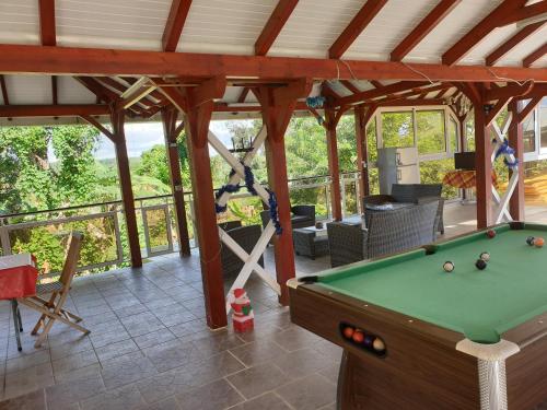 a screened in porch with a pool table at Atlantic Gites in Capesterre-Belle-Eau