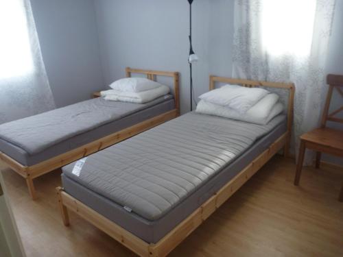 two twin beds in a room with a chair at Коттедж в Финляндии, Enonkoski (желтый) in Enonkoski