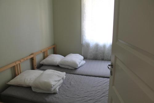 two beds with white pillows in a room with a window at Коттедж в Финляндии, Enonkoski (желтый) in Enonkoski