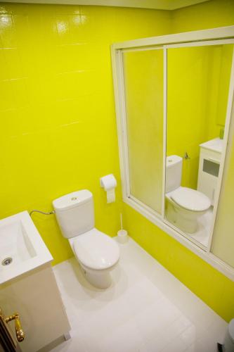 a yellow bathroom with a toilet and a sink at Pensión Parque del Ebro in Logroño