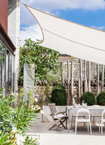 a patio with a table and chairs and a white umbrella at Le392Bis in Échiré