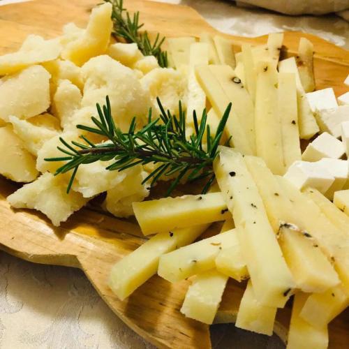 a wooden cutting board with cheese and rosemary on it at Il Nuraghe del lago Coghinas in Oschiri