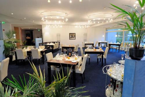 a dining room with tables and chairs and plants at Euro Park Hotel Hennef in Hennef
