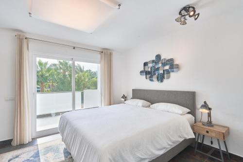 ein weißes Schlafzimmer mit einem Bett und einem Fenster in der Unterkunft Casa Bianca in Cala Vadella
